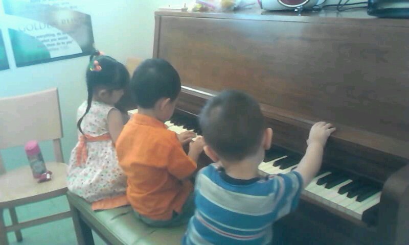 Three kids playing with the piano at church